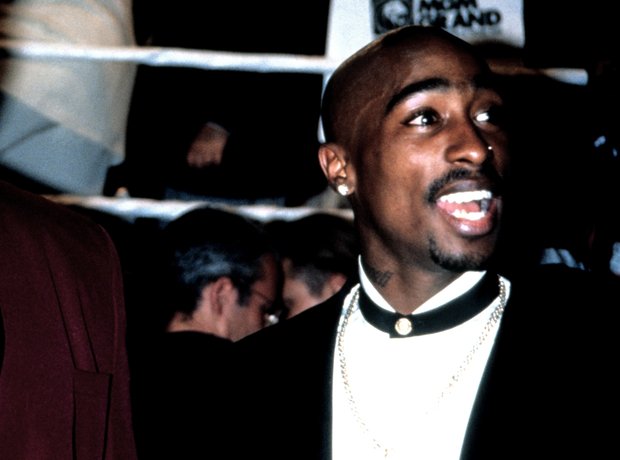 Tupac Shakur next to a boxing ring wearing a suit