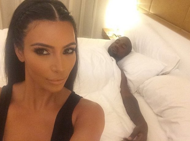 Kanye West in bed while Kim Kardashian takes a selfie