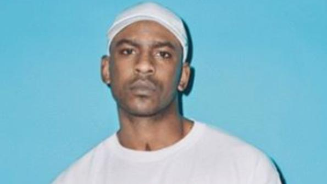 Skepta in front of a blue background