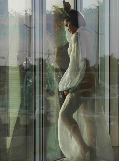 Rihanna leaning against window